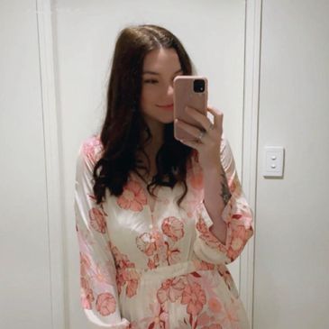 Woman taking a mirror selfie in a floral dress.