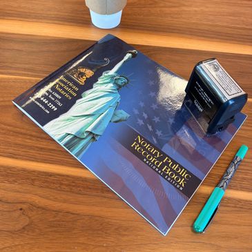 A notary public book, stamp, and pen next to a cup of coffee. 
