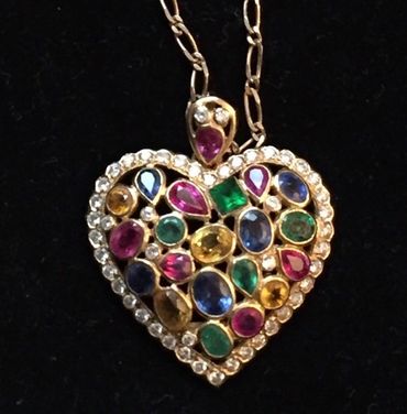 Heart-shaped pendant adorned with colorful gemstones and surrounded by small clear stones.