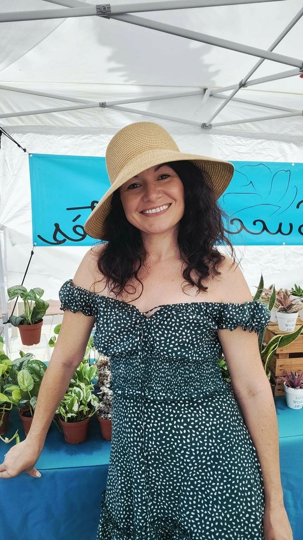 Woman in a sunhat smiles at a plant market stall.