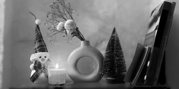 Cozy monochrome shelf with holiday decor and a candle.