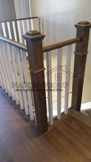 Wooden staircase railing with white balusters and dark wood posts.