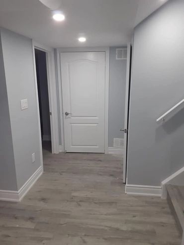 A clean, modern hallway with light wooden floors and white doors.