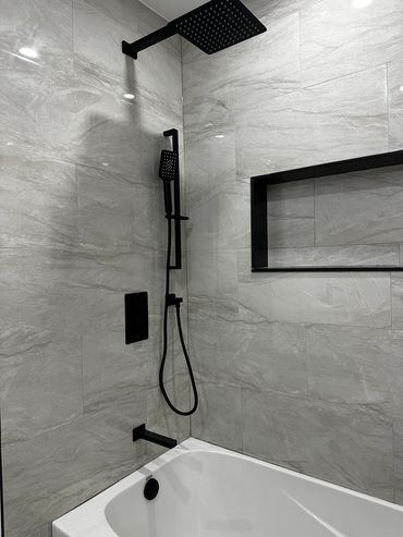 Modern bathroom with black fixtures and gray marble tiles.