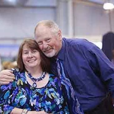 A couple smiling and embracing indoors.