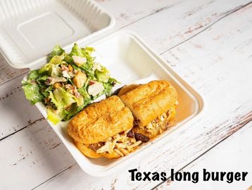 Takeout box with Texas long burgers and a fresh green salad.
