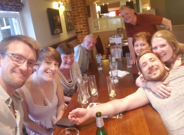 Photo of Pete and his family around a table with everyone smiling at camera