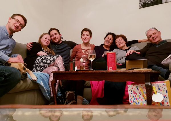 Photo of Pete and his family sitting on sofa with wine and presents sitting on table