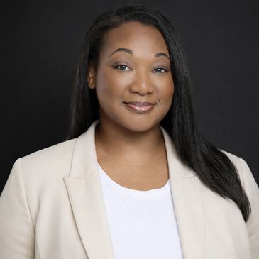 Confident woman in a beige blazer smiling against a black background.