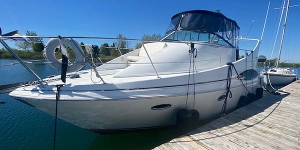 White motor yacht docked at a wooden pier on a sunny day.