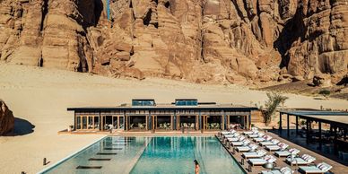 Luxury desert resort with pool and rocky cliffs backdrop.