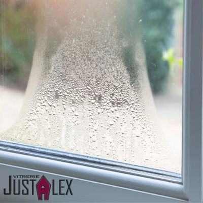 Condensation forming on a window with the logo of Vitrerie Just Alex.