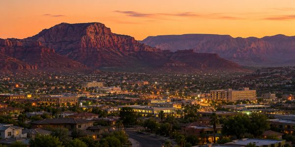 Cityscape at sunset with mountains in the background.