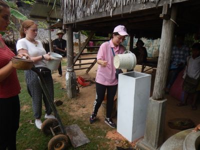 People engaged in an outdoor water activity near a rustic wooden structure.