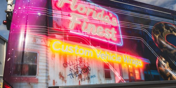 Bright neon sign advertising custom vehicle wraps in Florida.