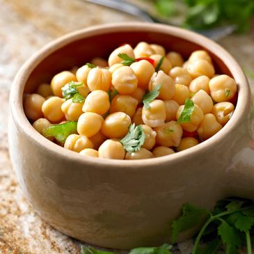 A bowl of cooked chickpeas garnished with fresh herbs.