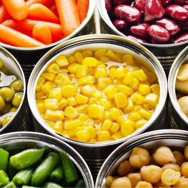 Open cans filled with various colorful canned vegetables and legumes.