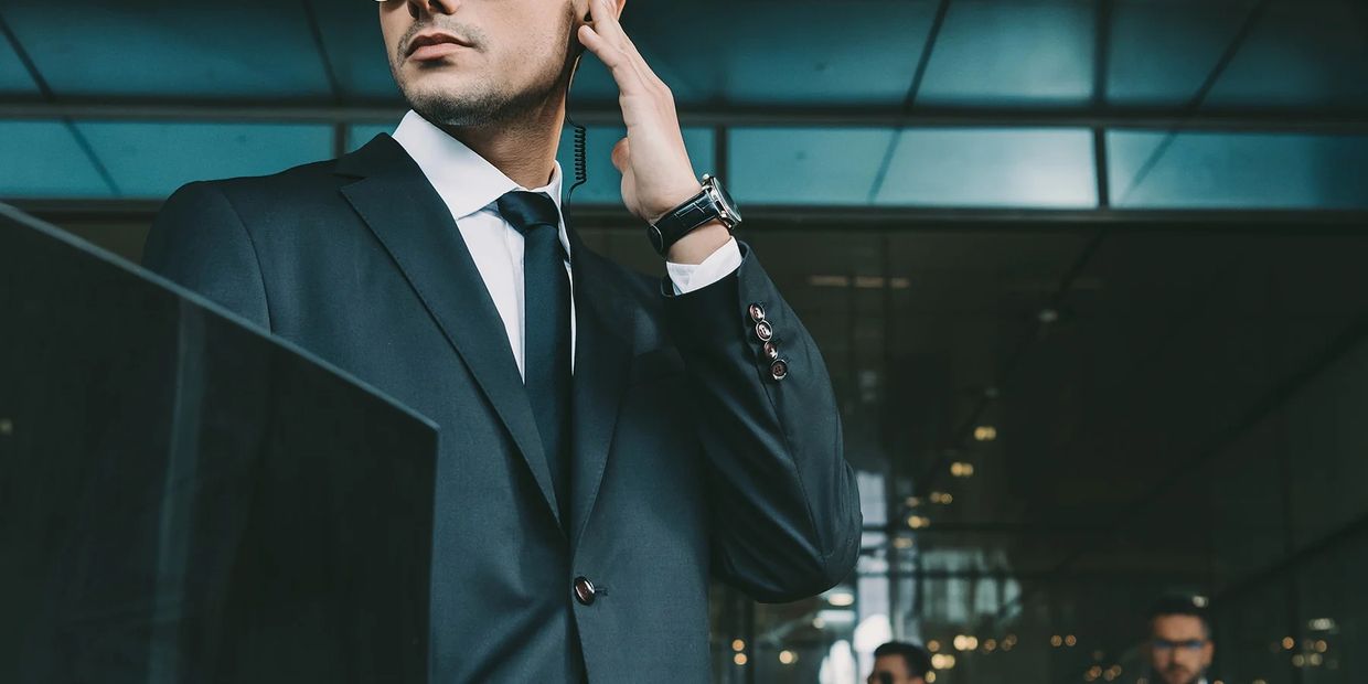 Man in a suit using an earpiece, appearing alert and professional.