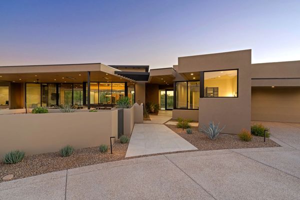 Modern desert home with clean lines and large windows at dusk.