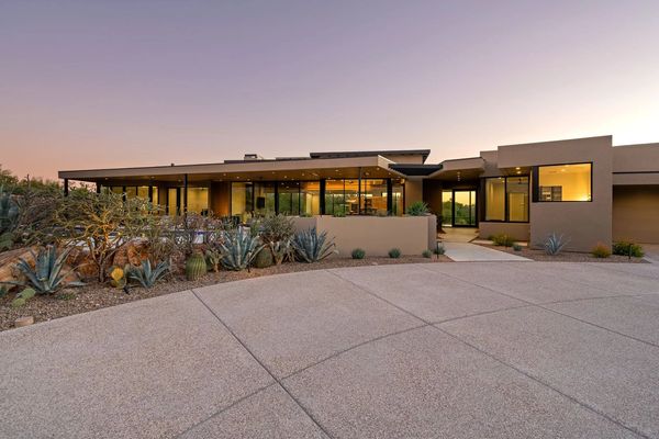 Modern desert home with large glass windows and minimalist landscaping.