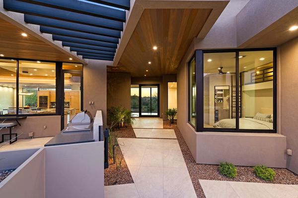 Modern house entrance with large windows and warm lighting.