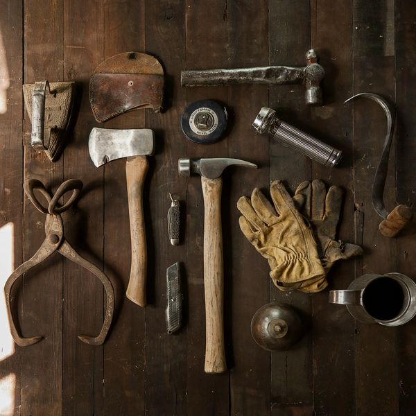 Vintage woodworking tools and gloves laid out on a wooden surface.