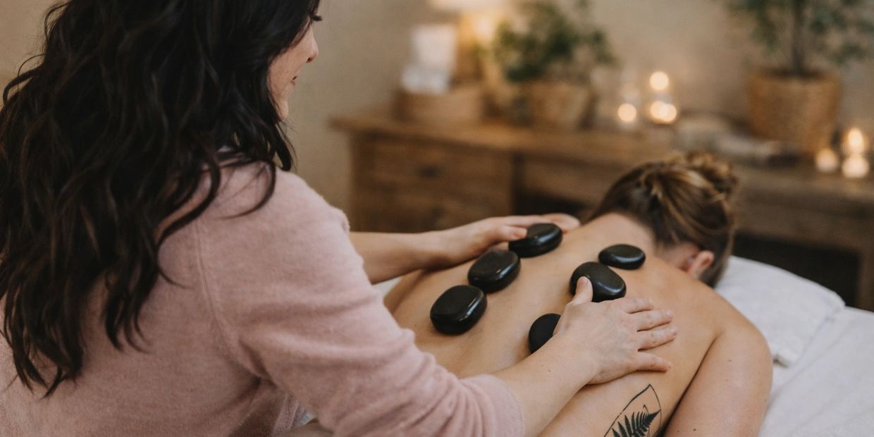 Hot stone massage treatment with heated stones placed along the spine for muscle relaxation
