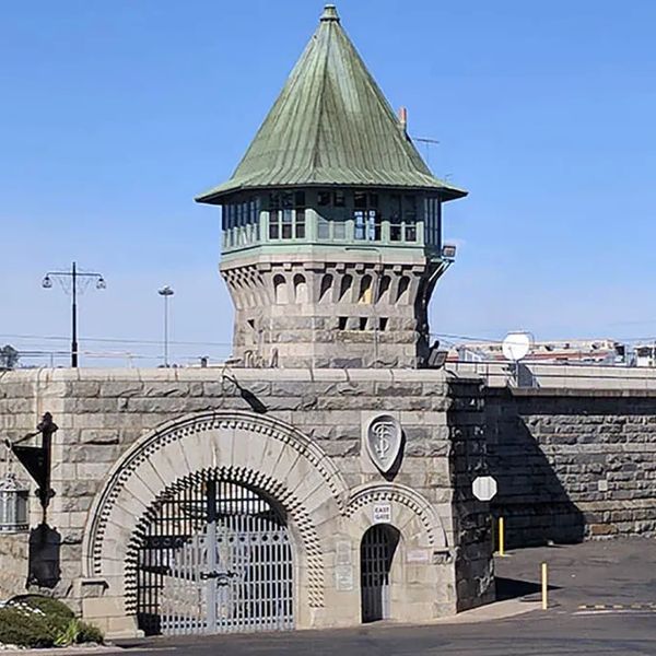 Historic stone prison entrance with a tall tower and iron gate.