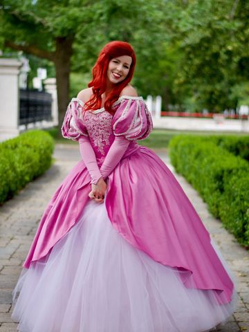 Sourire radieux d’une princesse en rose, posant avec grâce au cœur d’un jardin.