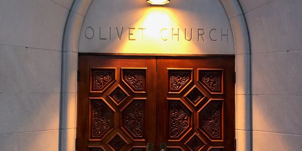 Ornate wooden doors of Olivet Church illuminated by a soft light.
