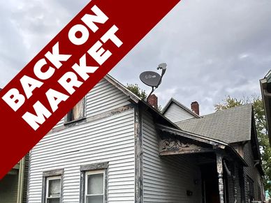 Old house with 'Back on Market' banner under cloudy sky.