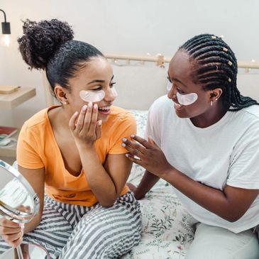 Two women enjoying skincare with under-eye patches at home.