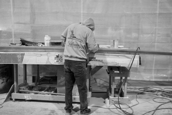 Worker in a workshop shaping a large boat component.