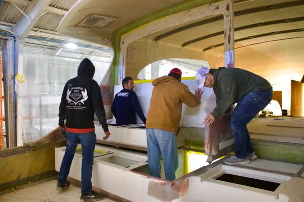 Four men working together on a boat interior construction project.