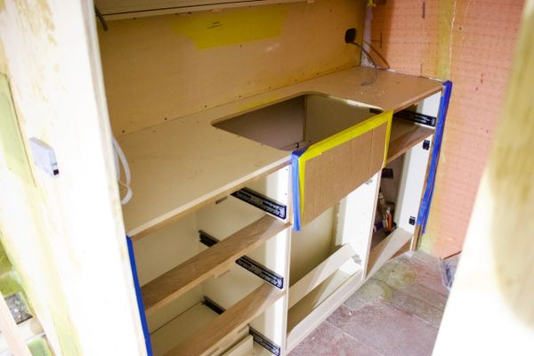 Partially installed kitchen cabinet with a cutout for a sink.