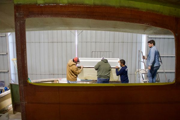 Four men working together on a boat interior in a workshop.
