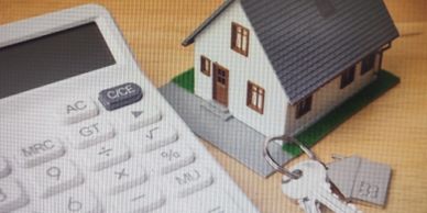 Calculator, model house, and keys on a table.