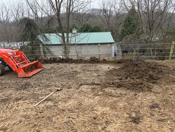 A muddy cleared area with a tractor and a shovel nearby.