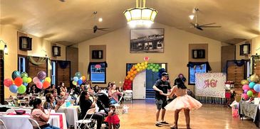 A couple dancing in a decorated hall with seated guests.