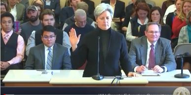 A woman takes an oath in a formal meeting room.