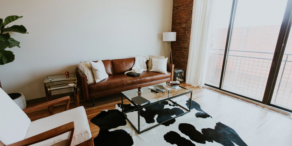 A therapist office with a leather couch, chair and large window with natural light