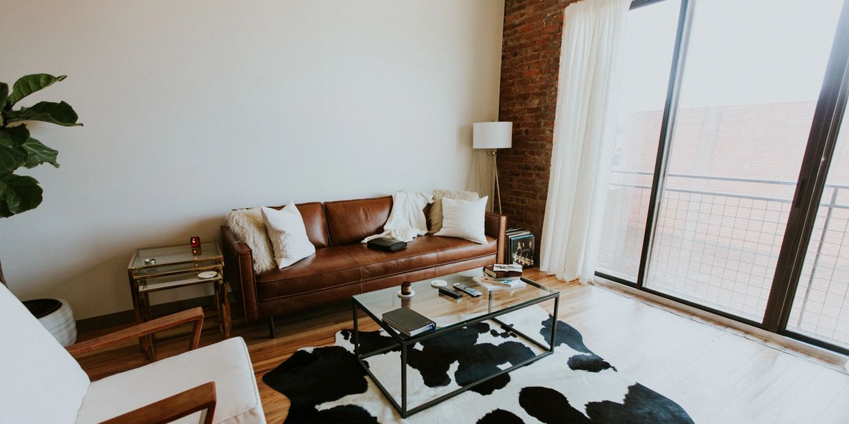 A therapist office with a leather couch, chair and large window with natural light