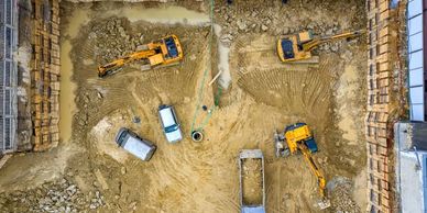 Aerial view of a construction site with excavators, trucks, and vehicles in operation.