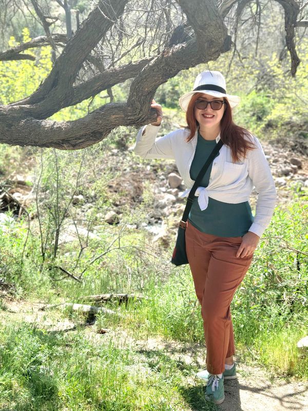 Lara Selene Scott standing with her hand on a tree branch at Boyce Thompson Arboretum