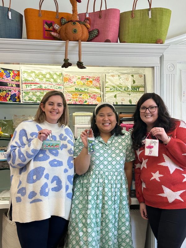 Group of people smiling with finished needlepoint ornaments
