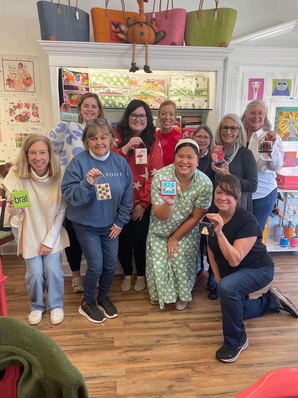 Group of people smiling with finished needlepoint ornaments