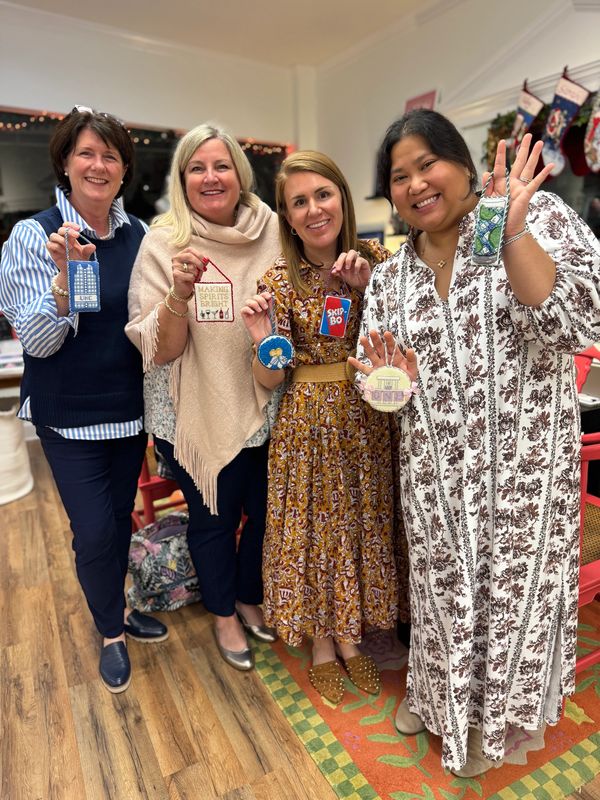 Group of people smiling with finished needlepoint ornaments