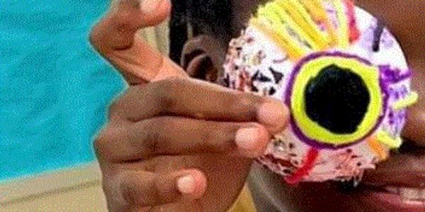 Person holding a colorful, decorated eyeball-shaped object.