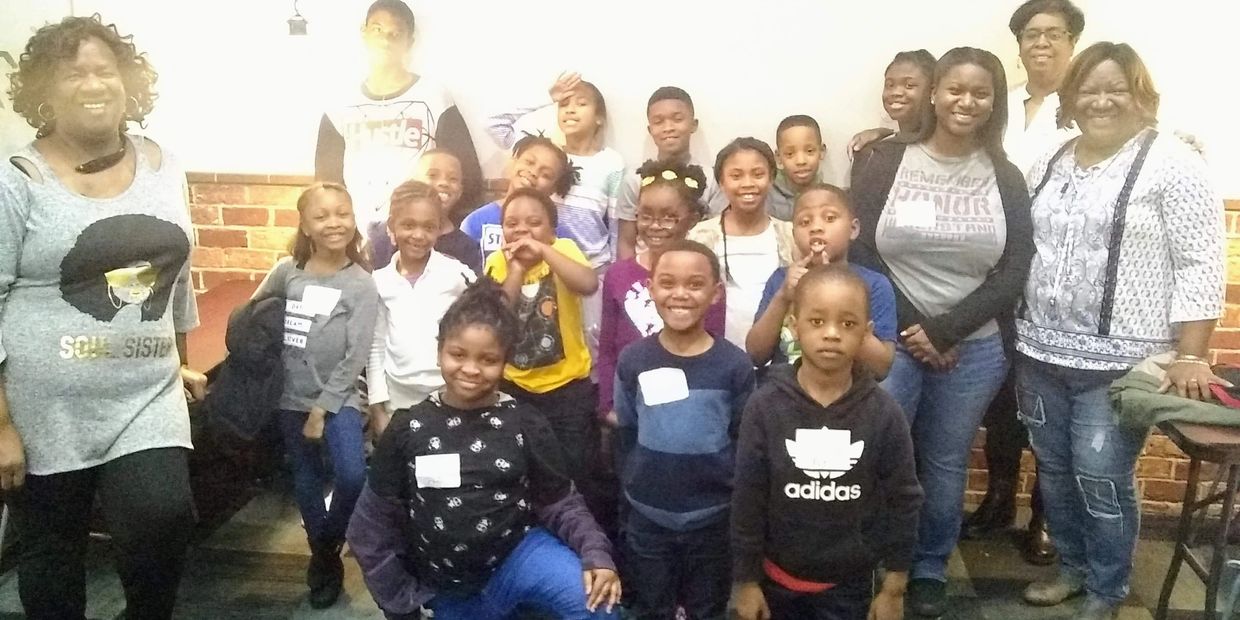 A joyful group of children and adults posing indoors, smiling at the camera.