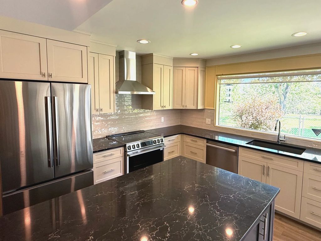 Modern kitchen with stainless steel appliances and black countertops.